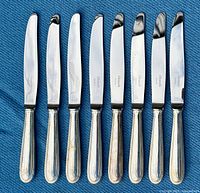 Front view of all eight Christofle Perles dinner knives