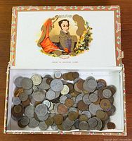 Open Bolivar Habana cigar box filled with assorted coins