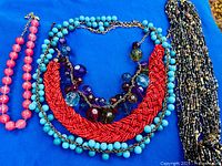 All five necklaces laid out on blue background