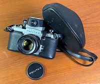 Camera with lens, cap and case on wooden surface