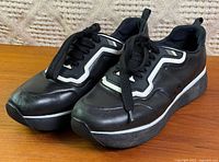 Three-quarter front view of both sneakers showing uppers, laces, reflective trim, platform soles