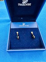 Open Swarovski box showing both black crystal drop earrings