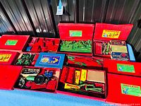 Overview of ten red Meccano boxes, some open showing green and red metal parts