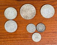 All seven coins front side on wood surface