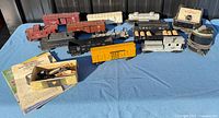 Overview of all Lionel O-gauge cars, tender, transformer, manuals and accessories on blue surface