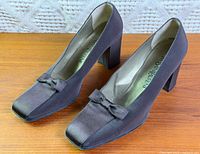 Pair of brown satin pumps with bows, side view