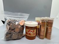 Bag of loose copper cents, pill container, and four coin tubes filled with cents