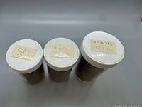 Three labeled jars with white lids containing wheat cents