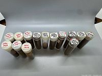 Top view of 14 coin tubes with handwritten year labels 1950-1959