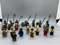 Front view of all 23 LEGO minifigures with weapons and shields displayed