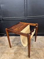 Front angle of rosewood side table highlighting tabletop grain and canvas magazine sling