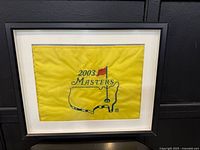 Front view of framed yellow 2003 Masters flag