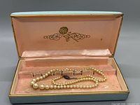 Opened case showing pearl necklace and clasp