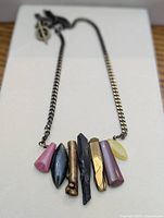 Full view of necklace laid flat showing chain, pendants and clasp