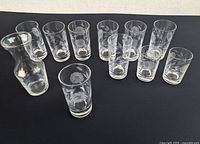 Group shot of eight tumblers, two juice glasses, one small vase on black background