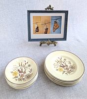 Stacks of small and large Jasmine plates beside framed butterfly print