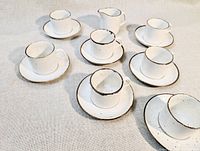 Full set laid out showing six cups, seven saucers and creamer