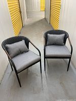 Two assembled gray-cushioned wicker dining chairs in hallway