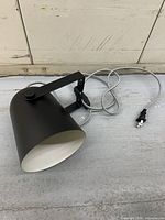 Side view of matte black wall sconce with bracket and braided cord