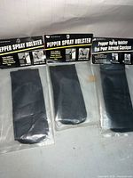 Three packaged Security Equipment Corporation pepper spray holsters on floor