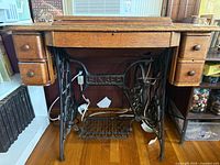 Front view of Singer treadle sewing table showing drawers, cast iron base, and absence of machine