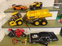 Group shot of all six assembled LEGO Technic models on steps