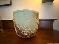 Front view of ceramic planter showing glaze and pinecone relief