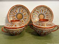 Front view of both lidded teacups and saucers