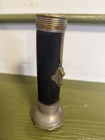 Full view of flashlight showing black ribbed body and metal ends