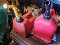 Two plastic gas cans side by side showing color, spouts, and wear