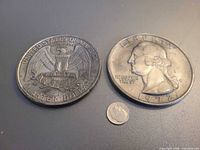 Obverse and reverse views of the oversized quarter replicas with a real dime for scale