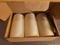 Open box showing three ivory LED candles and remote still wrapped