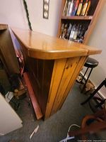 Full side view of the wooden bar showing paneled construction and foot rail