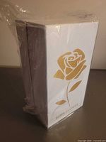 Front view of sealed white box with gold rose graphic