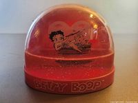 Overall view of Betty Boop red snow globe inside red-tinted dome on logo base
