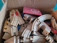 Top view of box filled with various wooden train tracks and red roof panel