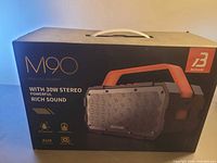 Front of boxed Bugani M90 Bluetooth speaker showing product image and 30 W stereo call-outs