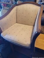 Front view of upholstered barrel armchair showing fabric pattern and wood trim