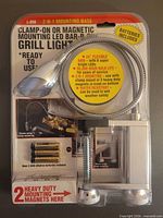 Front view of sealed package showing LED grill light, flexible arm, clamp mechanism and package text