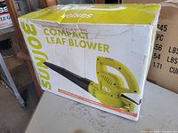 Front of sealed retail box showing Sun Joe 6-amp electric compact leaf blower model SBJ597E