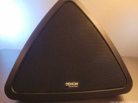 Front view of triangular Denon Professional speaker with grille and logo