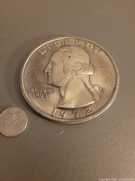 Obverse of oversized 1972 quarter next to regular coin for scale