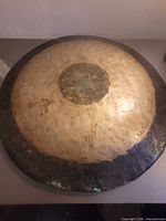 Front of hammered metal gong showing patina