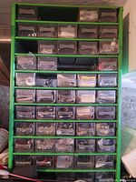 Full view of green cabinet with multiple transparent drawers containing hardware