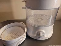 Front view showing base with timer dial, clear steaming chamber, basket