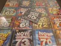 Group shot of all sealed NOW CDs laid out; volume numbers visible