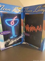 Front view of both boxed neon lamps showing Martini Glass and Whatever designs
