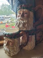 Three large ceramic Santa face mugs stacked to show overall design, handles, and size
