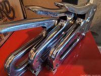 Three chrome handheld staplers stacked, showing lever handles and bodies