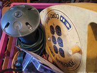 Yellow Coleman Powermate cord reel and green power stake among cords